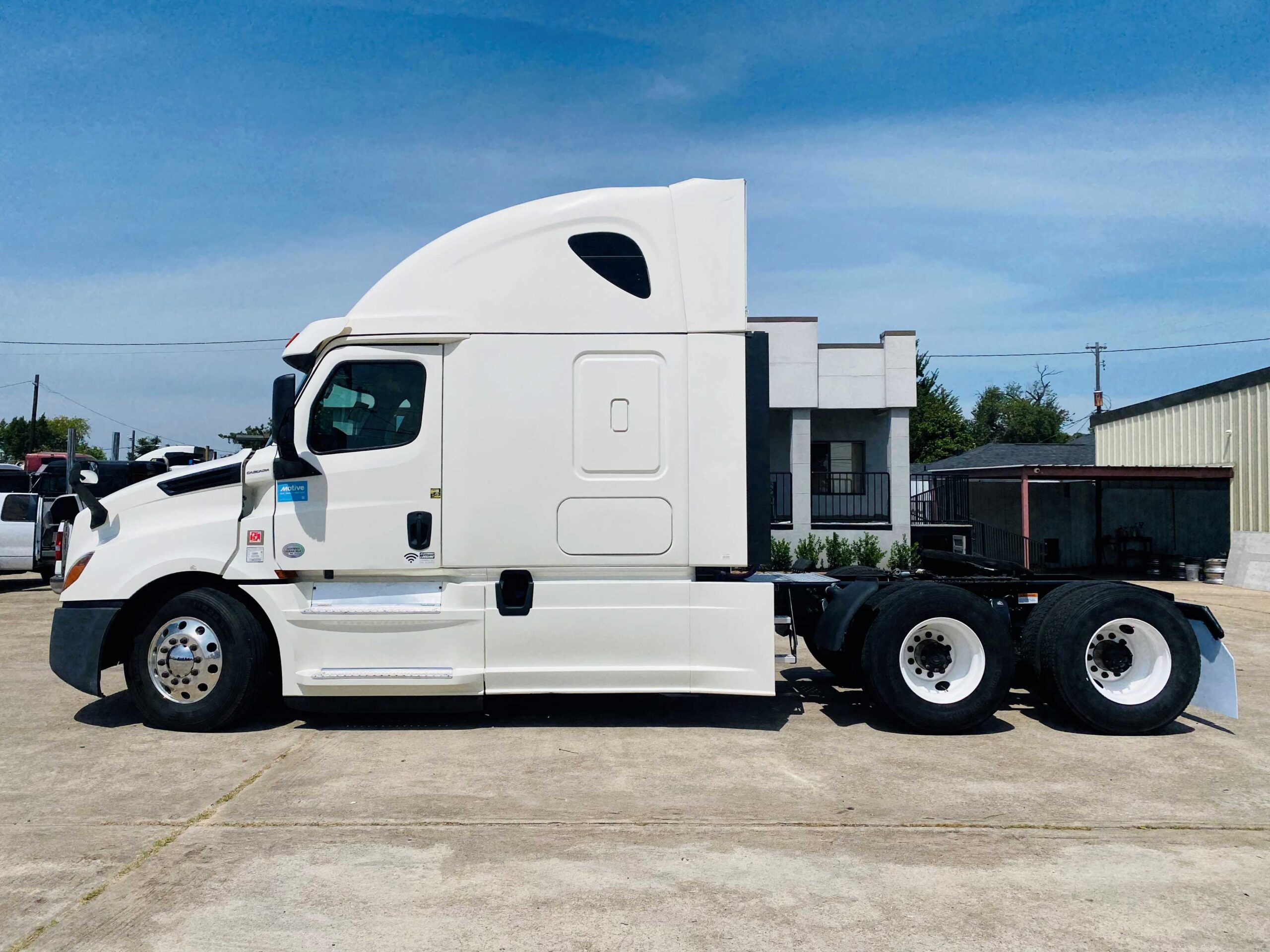 White semi-truck parked on concrete lot.