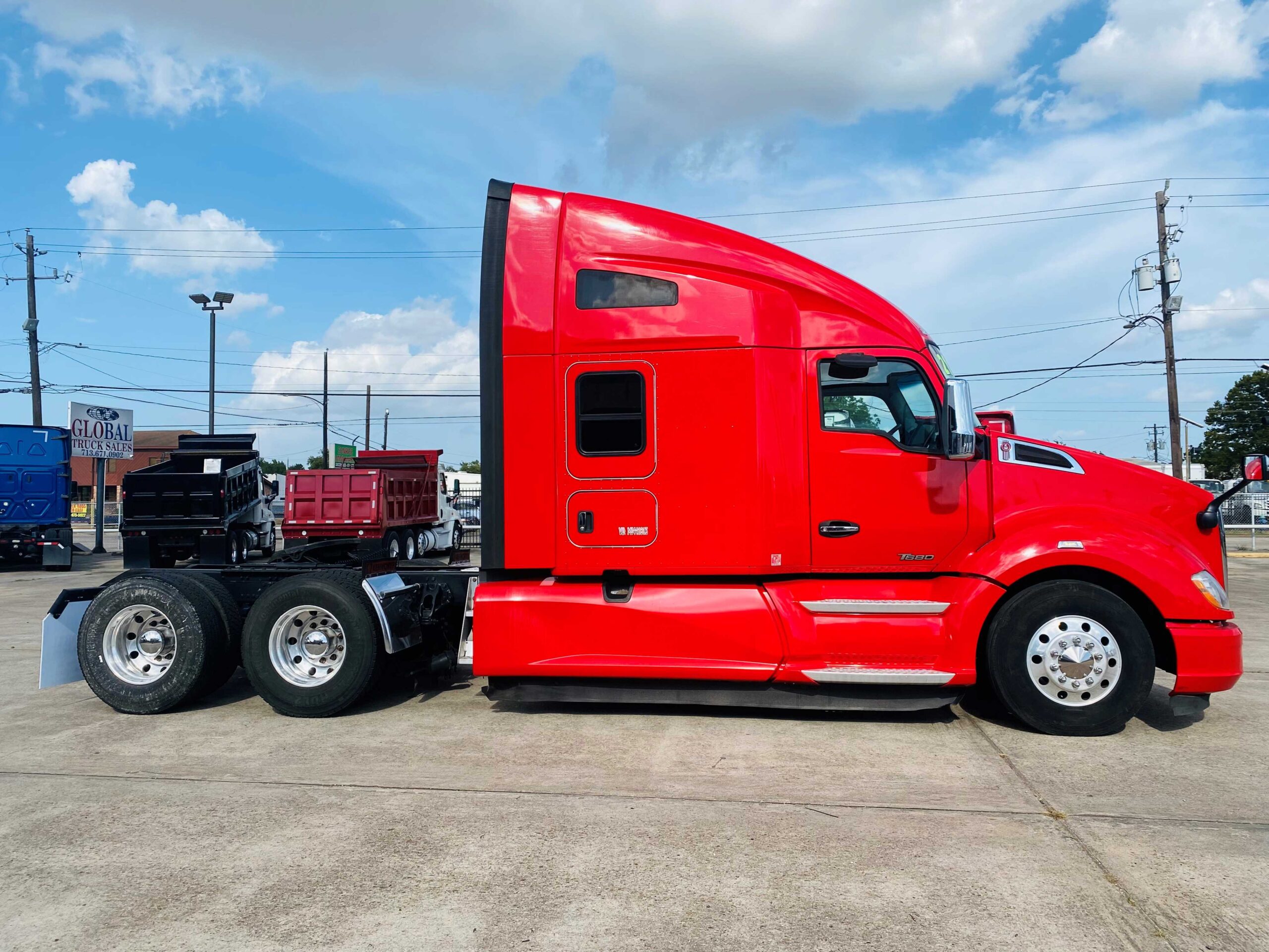 Red semi-truck parked on concrete lot.