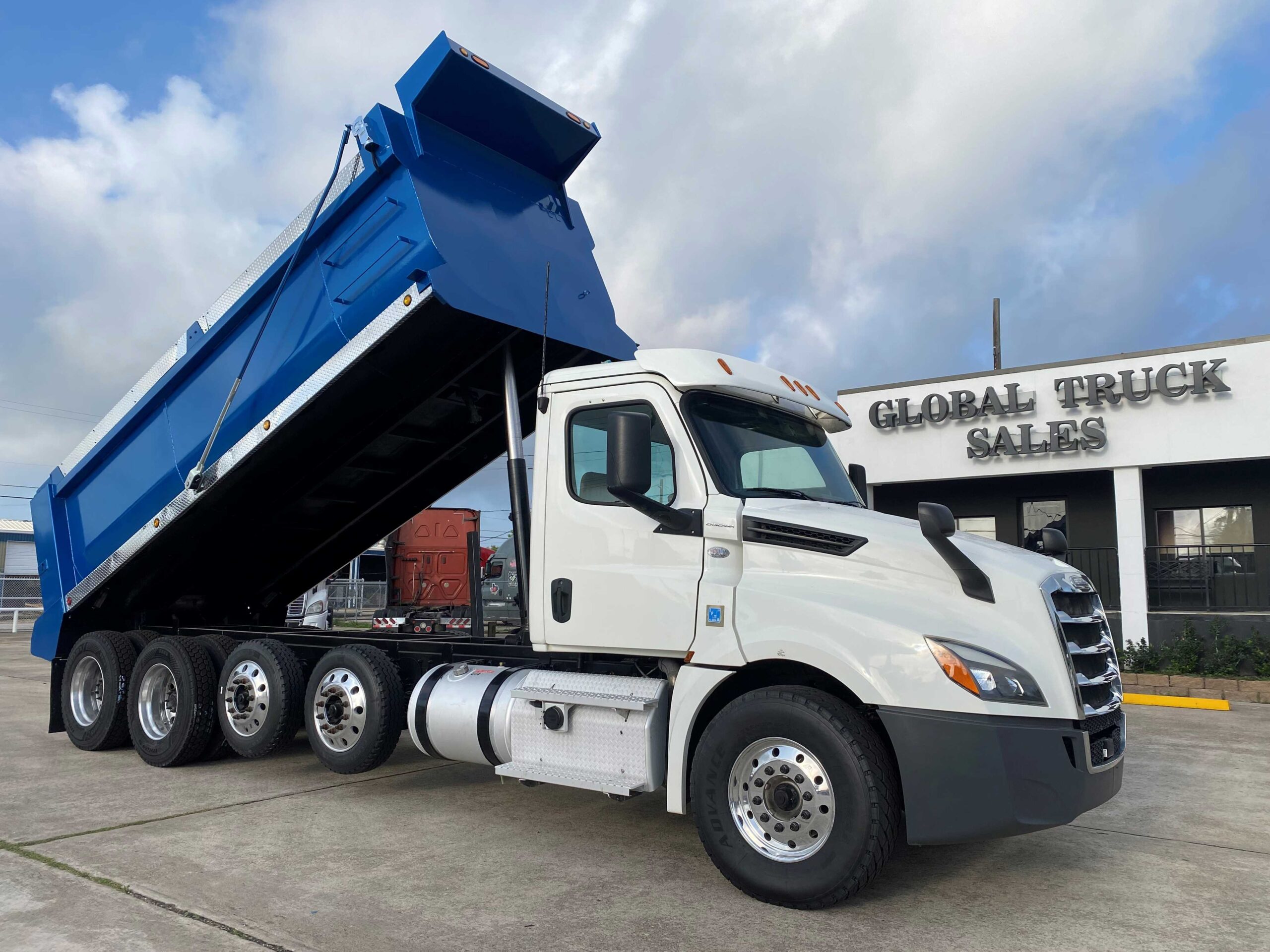 White dump truck with blue trailer raised.