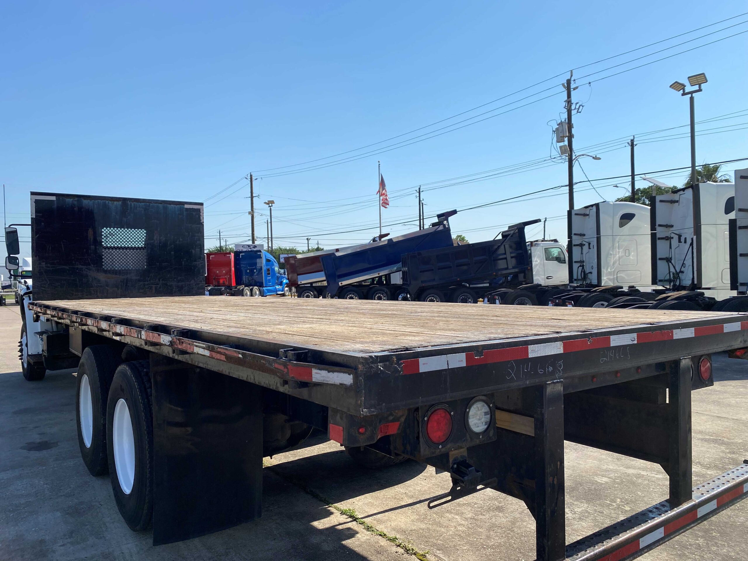 Empty flatbed trailer under clear sky